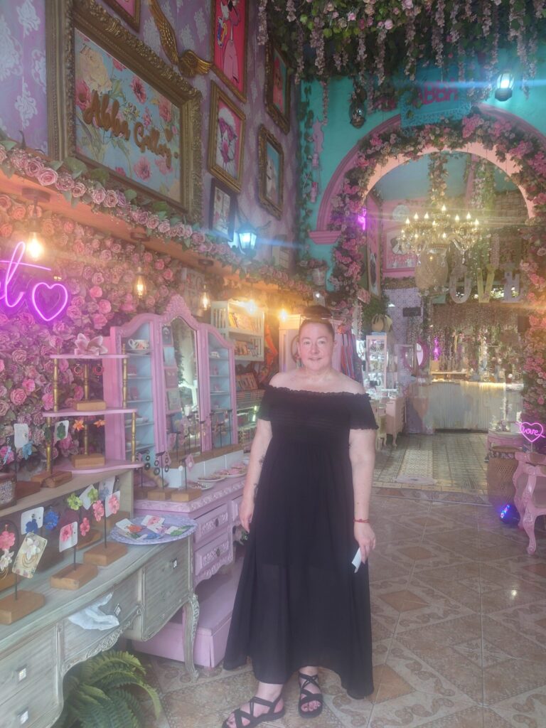Picture of the owner of Lotus & Luxe by Alyssa in a beautiful shop in Cartagena Colombia. The shop is decorated with roses along the walls and around an archway